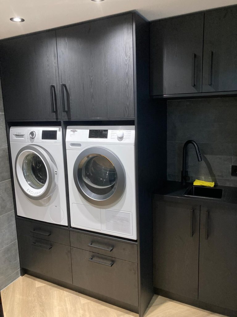 Wasmachine en droger ingebouwd in een zwarte kastenwand