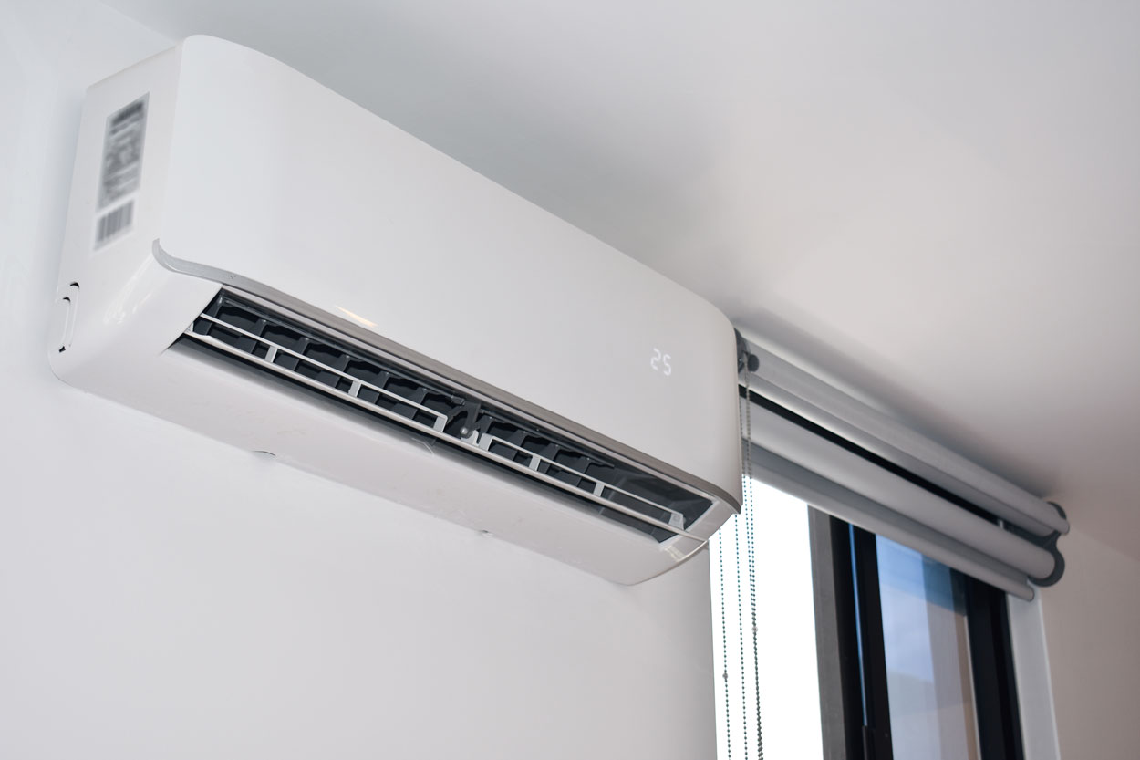 Airco-binnenunit hoog aan de muur naast een raam