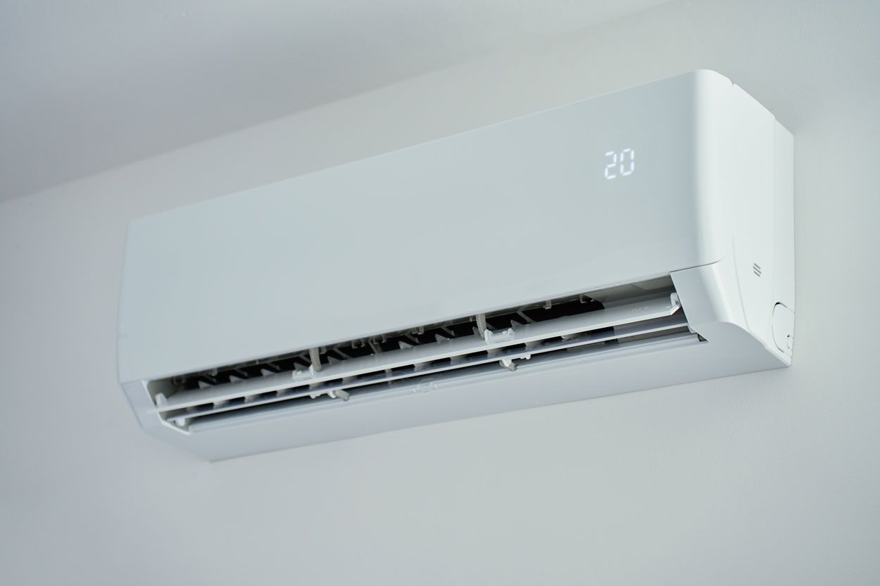 Witte airco-binnenunit aan de muur met temperatuurdisplay