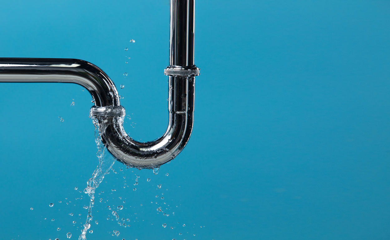 Lekkende verchroomde afvoerbuis met spattend water